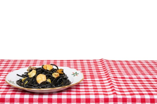 Table top on seafood background. Closeup of mediterranean black noodles with cuttlefish ink, mussels and shrimps on a red checkered tablecloth isolated on a white background.