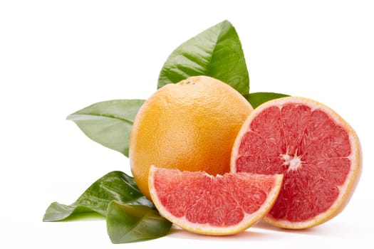 Fresh juicy whole grapefruit with green leaves and appetizing slices of ripe grapefruit on a white background.
