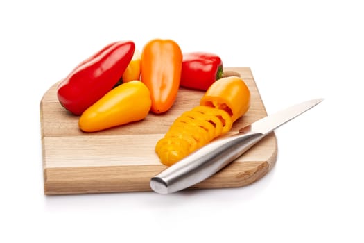 Fresh ripe peppers lying on wooden cutting board on a white background.
