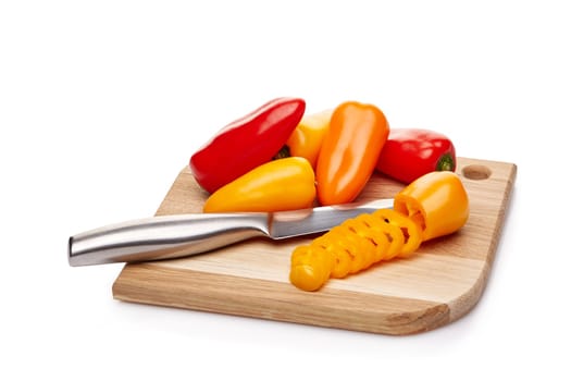 Fresh ripe peppers lying on wooden cutting board on a white background.