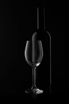 Silhouette of wine bottle and empty wineglass on a black background with reflection. Contour with gradient and highlights