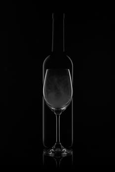 Silhouette of wine bottle and empty wineglass on a black background with reflection. Contour with gradient and highlights