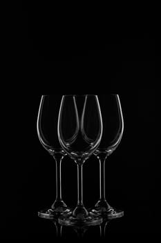 Silhouette of three empty wineglasses on a black background with reflection. Contour with gradient and highlights