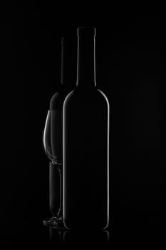 Silhouette of two wine bottles and empty wineglass on a black background with reflection. Contour with gradient and highlights