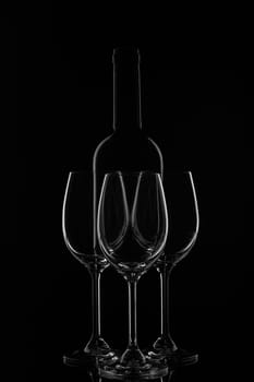 Silhouette of wine bottle and three empty wineglasses on a black background with reflection. Contour with gradient and highlights