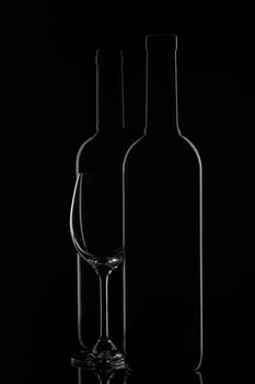 Silhouette of two wine bottles and empty wineglass on a black background with reflection. Contour with gradient and highlights