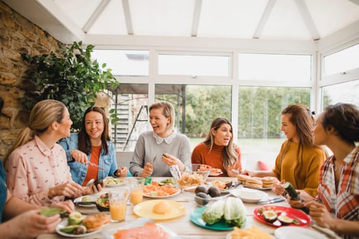 Small group of female friends preparing a healthy lunch inside of a conservatory on a weekend away.