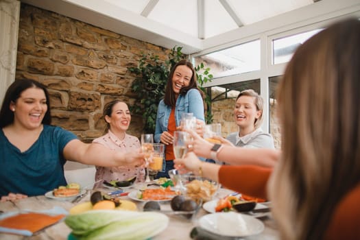 Small group of female friends preparing a healthy lunch inside of a conservatory on a weekend away. They are making a celebratory