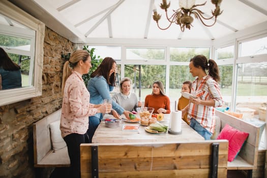 Small group of female friends preparing a healthy lunch inside of a conservatory on a weekend away.