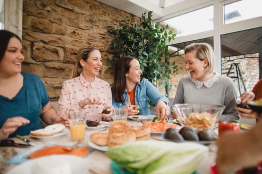 Small group of female friends preparing a healthy lunch inside of a conservatory on a weekend away.