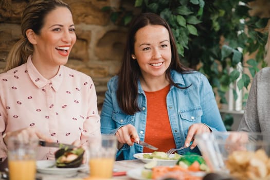 Two mid adult women listening and talking while eating a healthy meal.