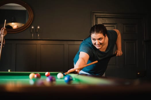 Small group of female friends playing a game of pool in a games room in a house.