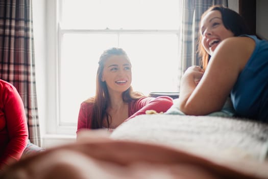 Young female adult sitting in a bedroom in her pyjamas while talking to her friends.