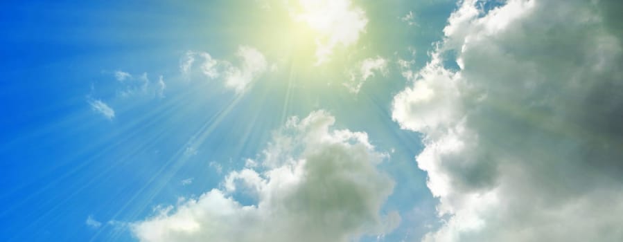 Rays of streaming sunlight on cloudy blue sky background. Summer, holiday, fun, banner, nature, concept.