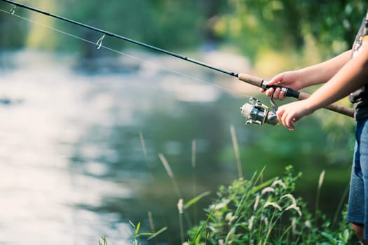 Fishing rod and reel in hands on the river