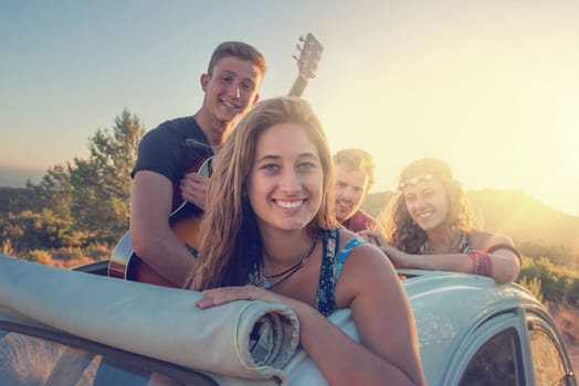 Group of happy people in a car at sunset in summer.