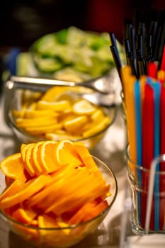 Orange, lemon and lime slices arranged on the glass bowl setting on holiday table. Focus on orange slices.