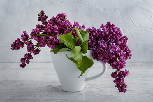 Lilac flowers in a white cup on the table