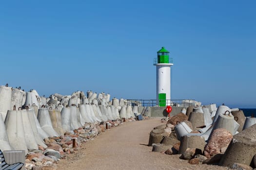 White lighthouse tower on blue sky background, Ventspils, Latvia