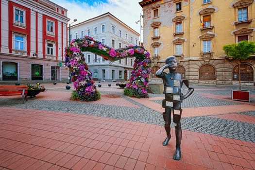 TIMISOARA, ROMANIA - April 21, 2019: Liberty Square (Piata Libertatii) in the foreground is a statue De-a telefonul (Playing on the phone) by Bogdan Rath