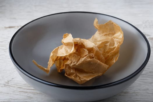 Crumpled brown paper in empty gray bowl