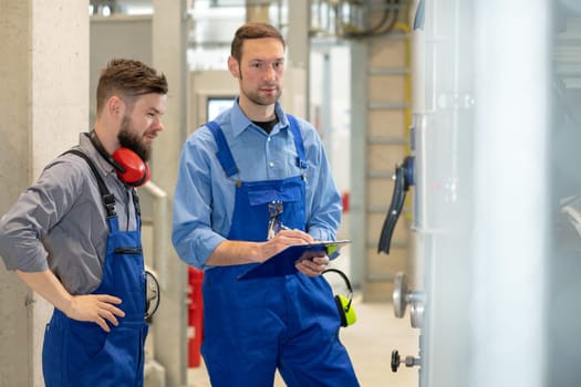 two worker in blue work clothes in industrial plant