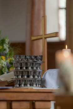 Church cross stands on an evangelical altar with a communion cup and blurred burning candle