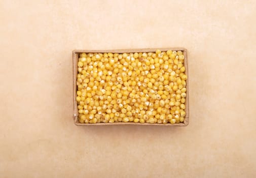 Raw millet in carton and on brown background