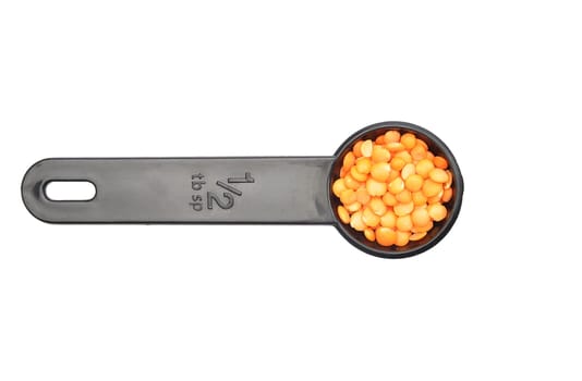 Red lentils on measuring spoon and white background