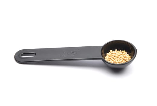 Mustard seeds in measuring spoon on white background