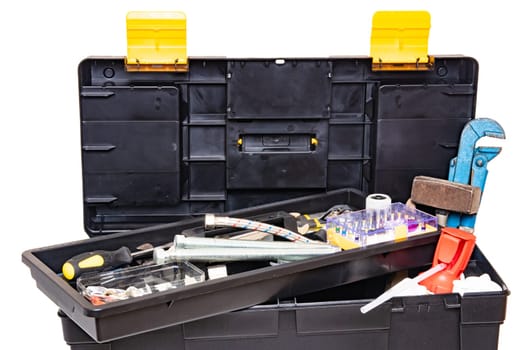 Tool box isolated. Black plastic tool kit box with assorted tools and with various nails, screws, fasteners as well as dowels isolated on a white background.