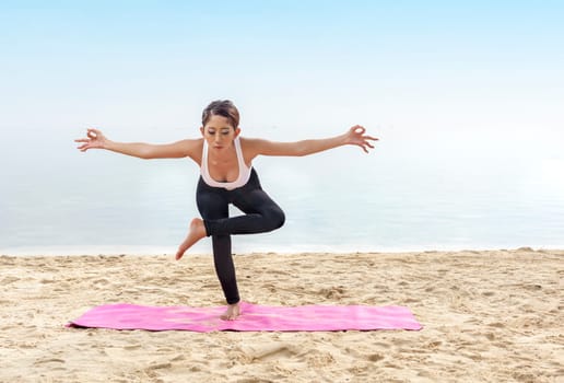 Asian healthy woman practicing yoga on the carpet in beach. Healthy concept