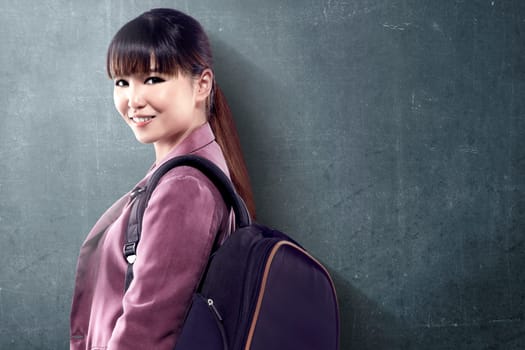 Asian student woman with backpack standing and look back with blackboard background. Back to School concept