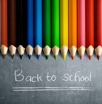 Row of colorful stationery of pencils for drawing on blackboard with Back to School message. Back to School concept