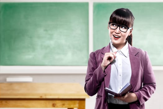 Asian student woman with notebook and pen thinking something in the classroom with chalkboard background. Back to School concept