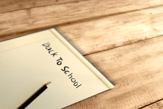 Paper and pencil with Back to School message on wooden table. Back to School concept