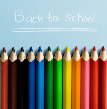 Row of colorful stationery of pencils for drawing on blue table with Back to School message. Back to School concept