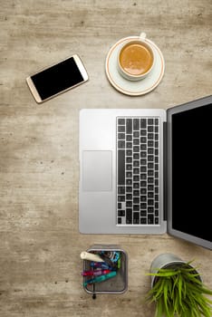Top view of business desk with laptop, coffee, potted plant, mobile phone and business accessories on the office