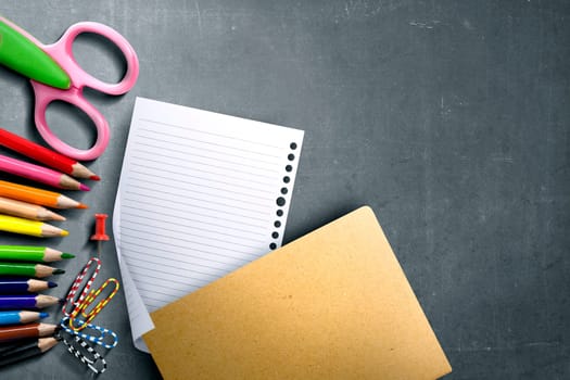 School supplies and stationery with white paper on blackboard with copyspace. Back to School concept