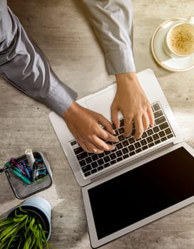 Top view of businessman working using laptop with coffee, potted plant and business accessories on the desk