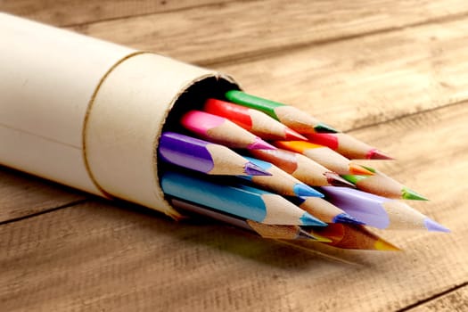 Rolled cardboard with colorful stationery of pencils for drawing on wooden table. Back to School concept
