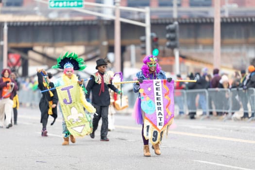 St. Louis, Missouri, USA - March 2, 2019: Bud Light Grand Parade, African american woman wearing a colorful outfit and a mask, holding a banner that says, celebrate 1984