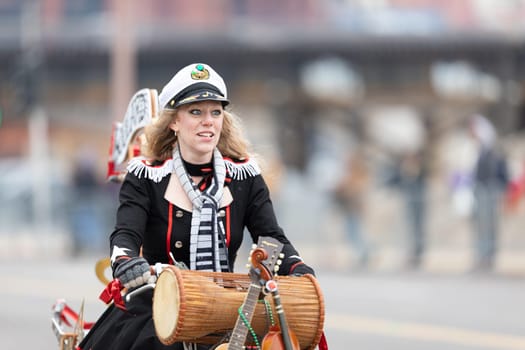 St. Louis, Missouri, USA - March 2, 2019: Bud Light Grand Parade, Woman riding a bicycle iwearing a captain outfit, going down 7th street during the parade