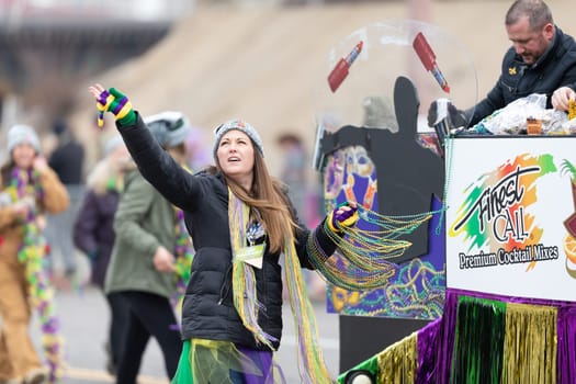 St. Louis, Missouri, USA - March 2, 2019: Bud Light Grand Parade, Woman walking down 7th street throwing beads to the spectators