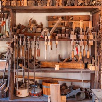 Shelf in a carpentry workshop with tools such as clamps, pliers, Hogel and other craft utensils.