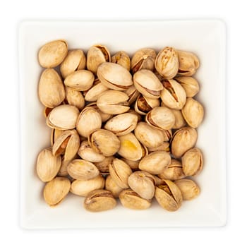 Unpeeled Pistachios in a bowl isolated on white background