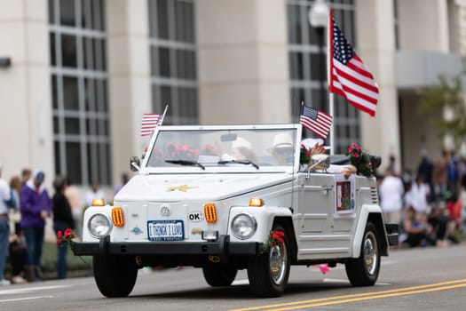 Wilmington, North Carolina, USA - April 6, 2019: The North Carolina.Azalea Festival, Man driving a classic Volkswagen with a woman holding the photograph of a member of the NC Army National Guard