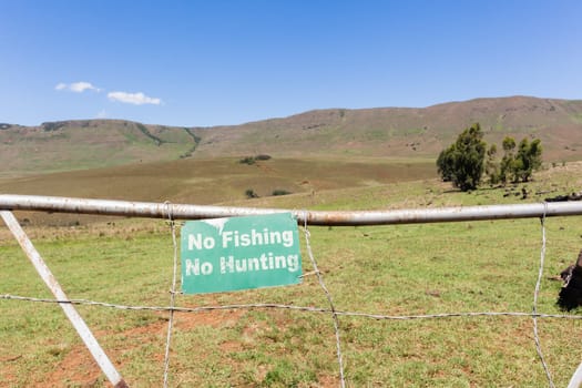 Mountains farm gate sign no-fishing no-hunting farmer property closeup photo.