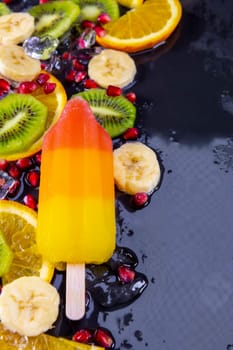 Fruit ice cream on stick with slices fruits on black slate board. Focus on Popsicles.