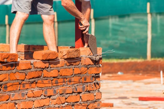 Building construction artisan hands tool laying bricks closeup cement wire wall construction